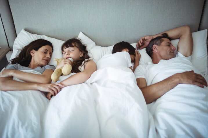 družinski člani spijo v postelji