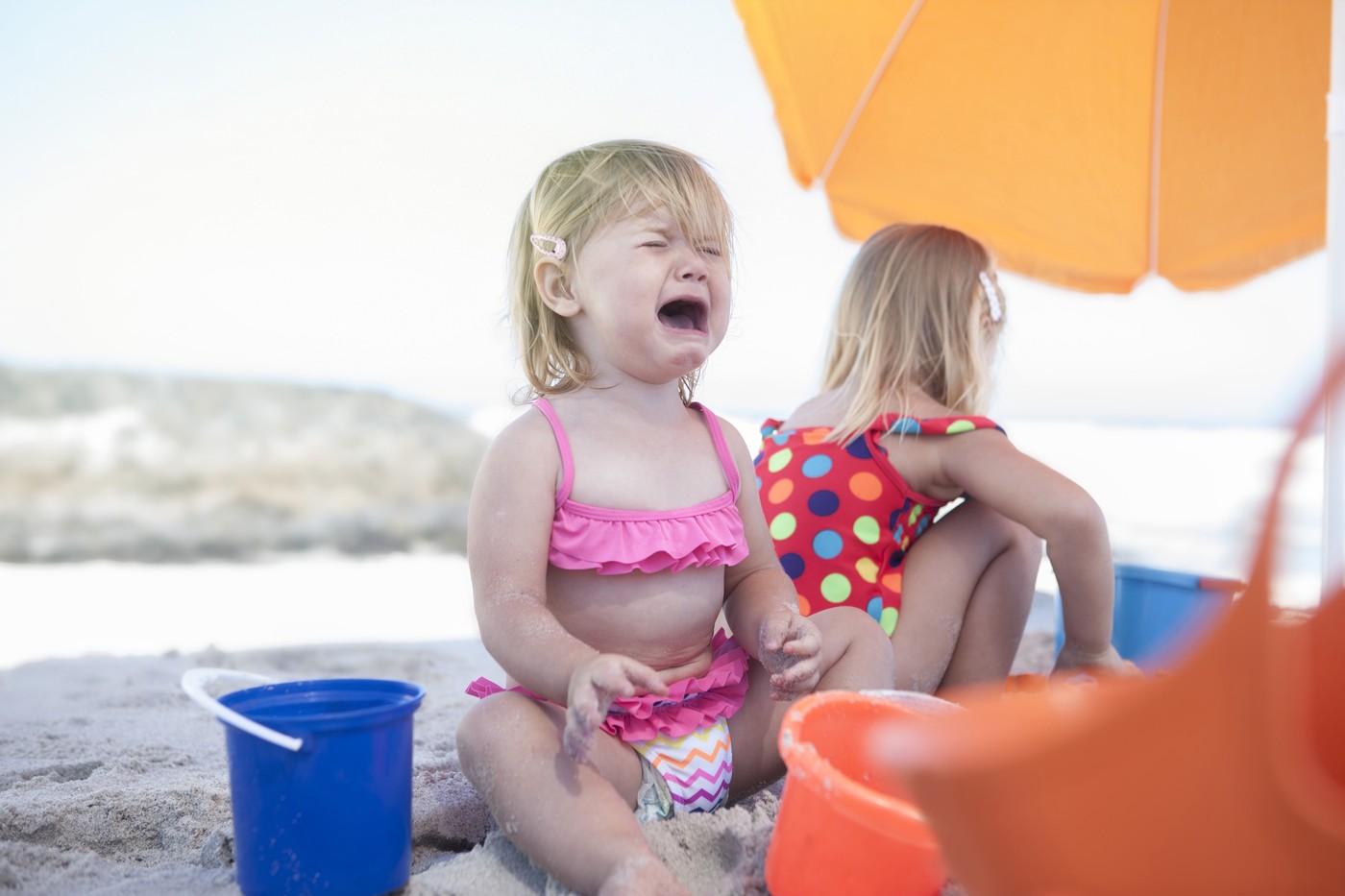 deklica sedi na plaži in joka
