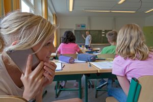 učenka uporablja mobilni telefon med poukom