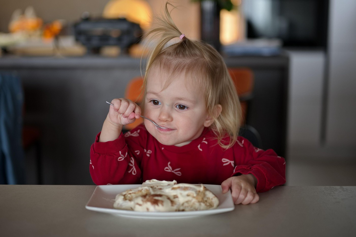 majhna deklica sedi za mizo in je torto
