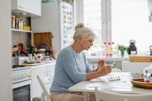 starejša ženska sedi za mizo v kuhinji