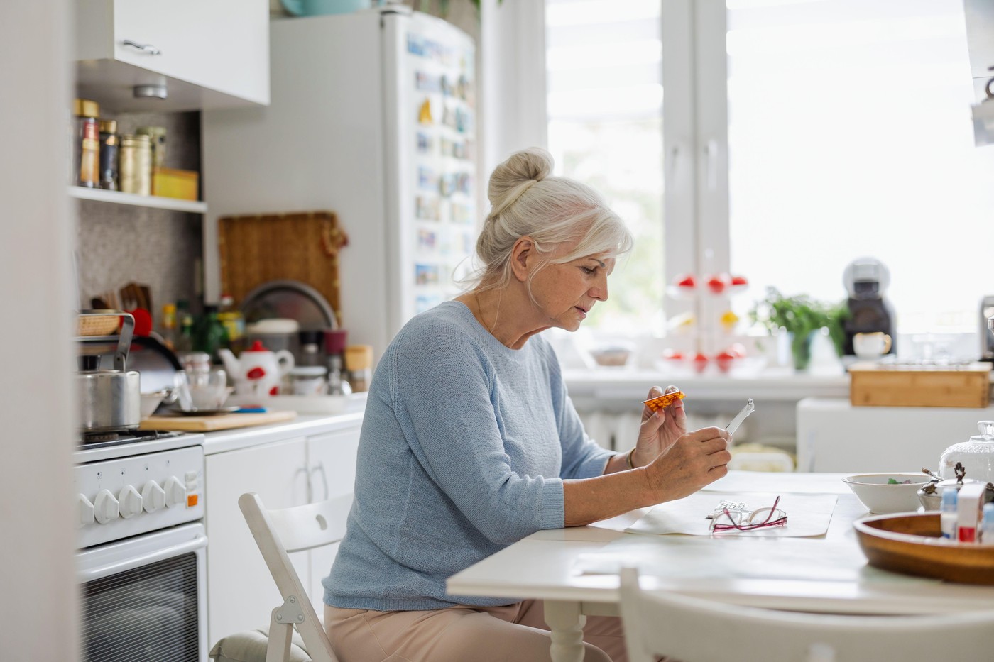 starejša ženska sedi za mizo v kuhinji