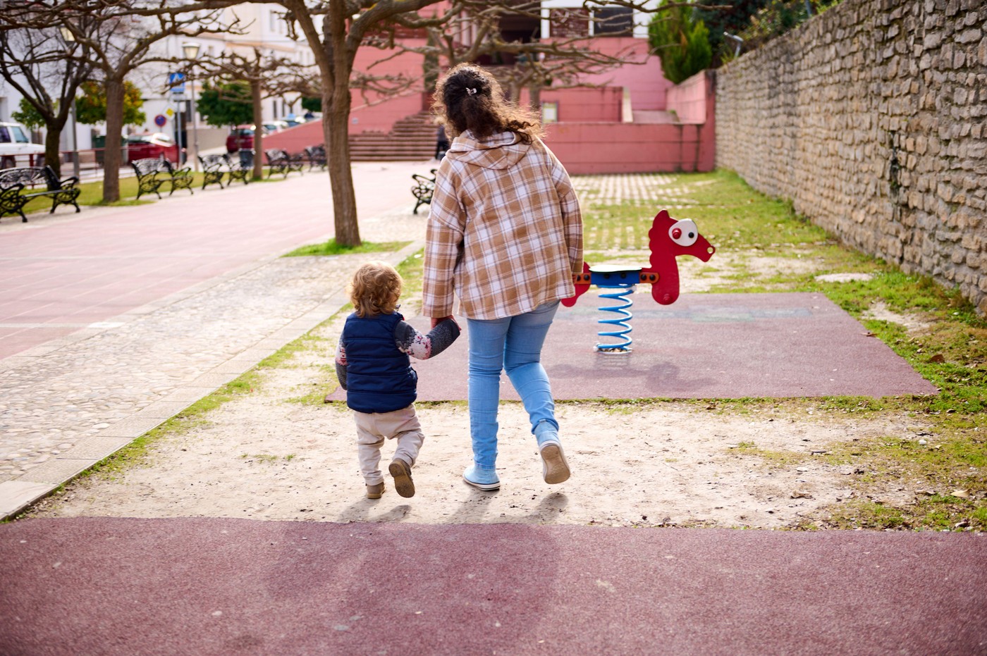 mama drži otroka za roko na igrišču