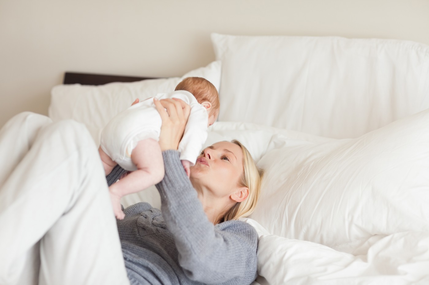 mama leži na postelji in se igra z dojenčkom