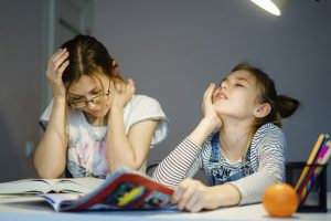 mama pomaga hčerki pri delanju domače naloge