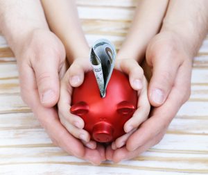 oče in sin z rokami držita hranilnik z denarjem