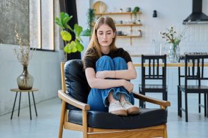 žalostna mlada ženska sedi na stolu