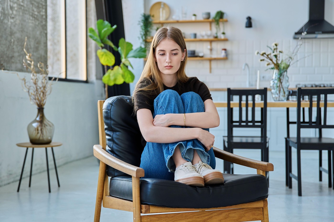 žalostna mlada ženska sedi na stolu