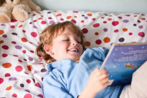 deček leži na postelji in bere knjigo