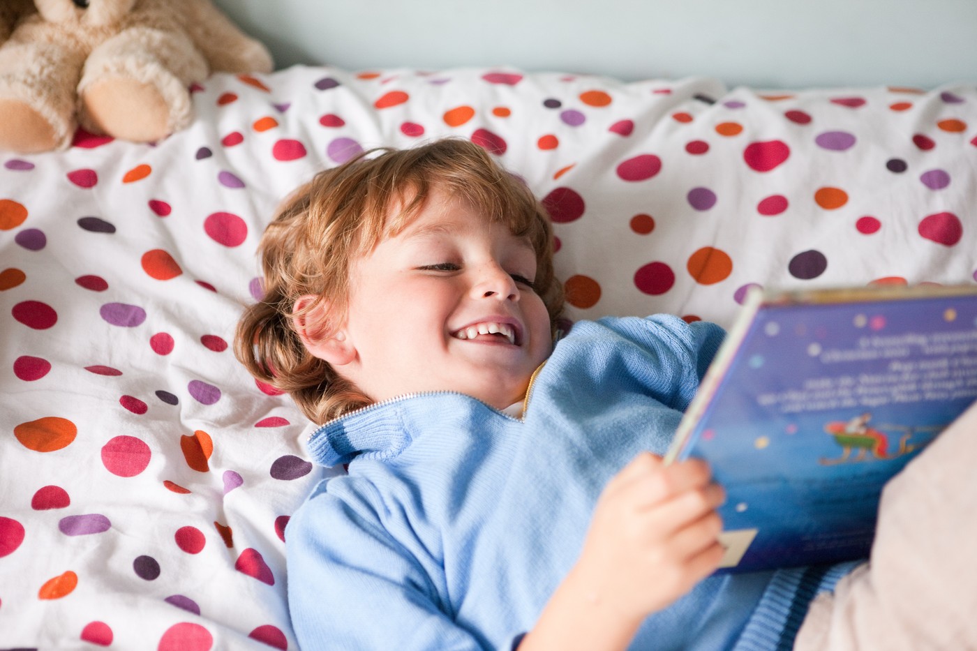 deček leži na postelji in bere knjigo