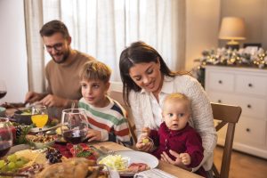 družina sedi za praznično mizo mama oče otroka