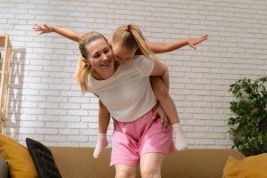 nasmejani mama in hči, mama nosi hčerko na hrbtu