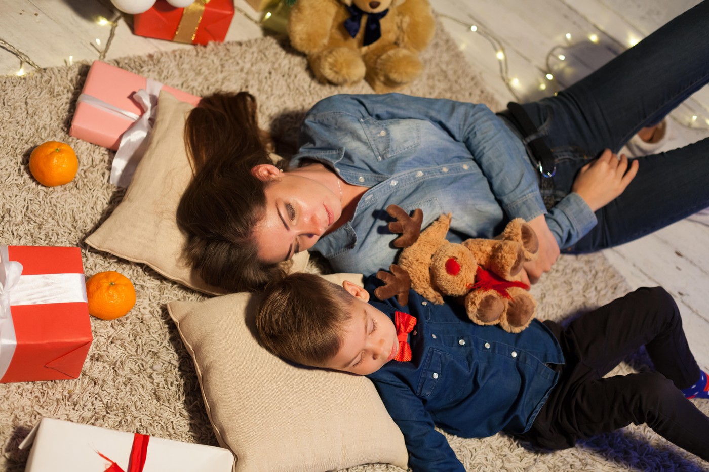 mama in sin ležita na tleh poleg daril v božičnem času