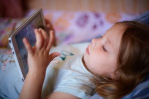 majhna deklica gleda risanko na tablici