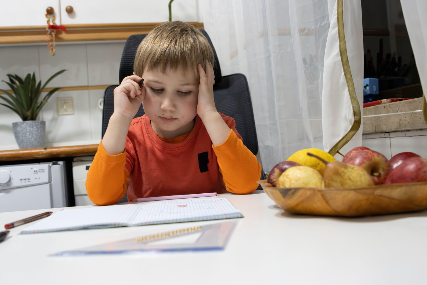 otrok dela domačo nalogo v kuhinji