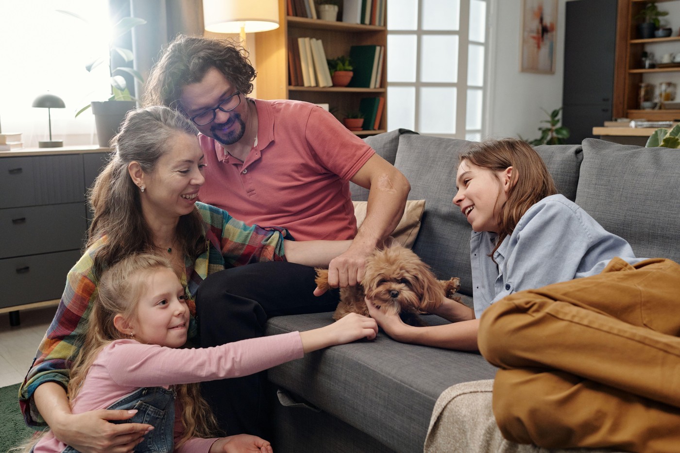 družina v dnevni sobi boža psa