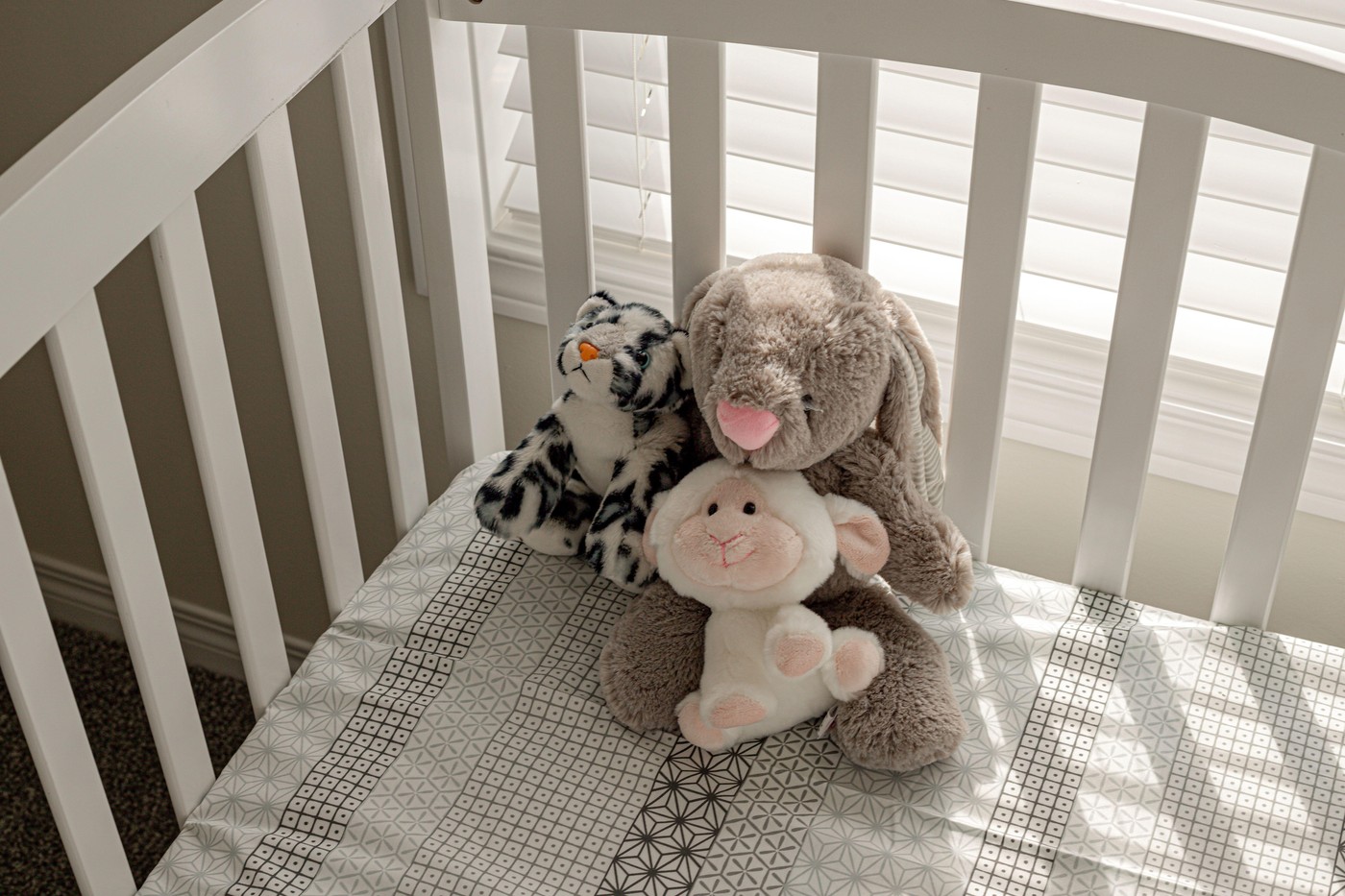 tri plišaste igrače v prazni posteljici