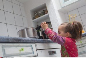 deklica se steguje k posodi, ki je na pultu