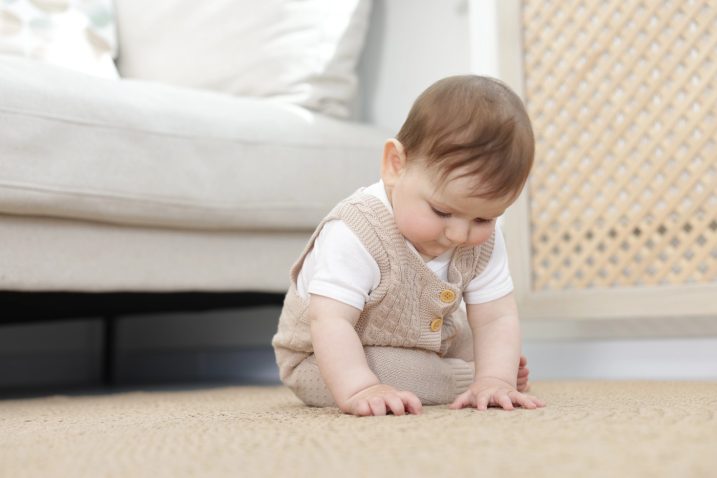 dojenček samostojno sedi na tleh