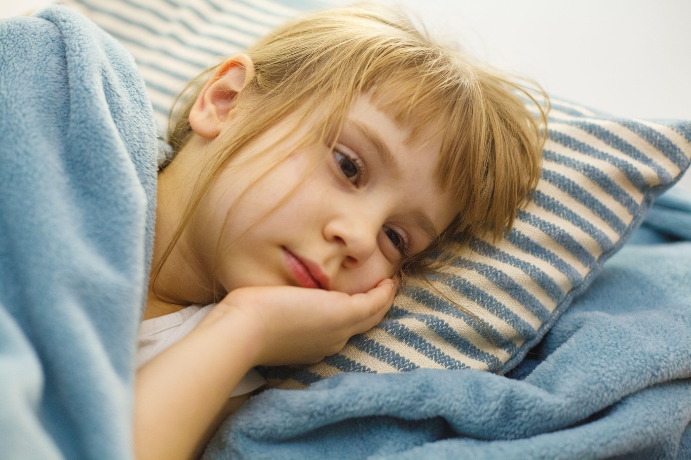 utrujena deklica leži na postelji