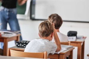 ucenec sedi v klopi in se drži za glavo