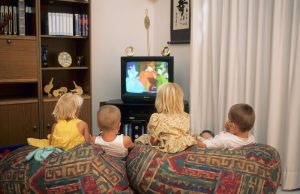 štirje mlajši otroci na kavču gledajo televizijo