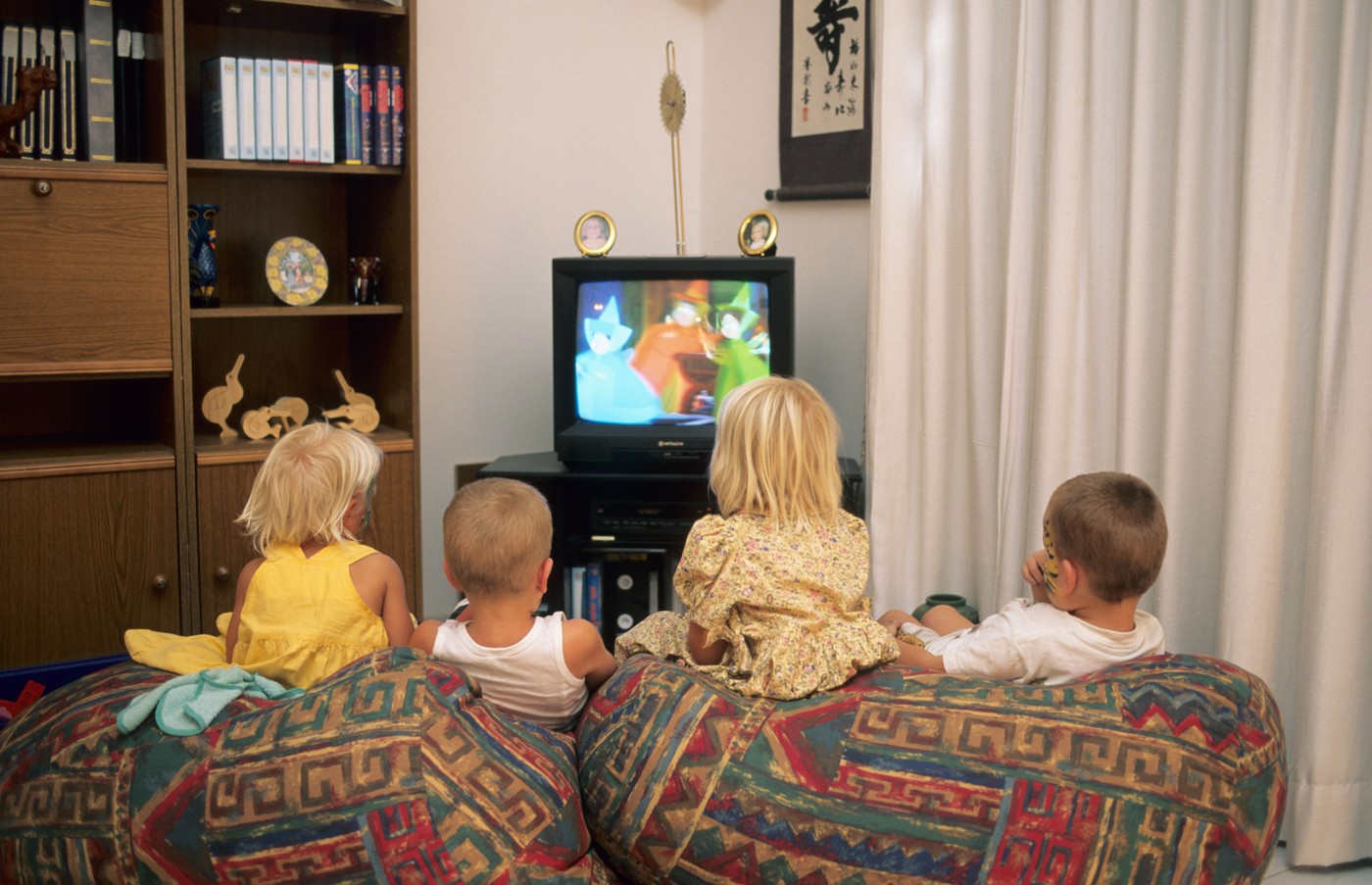 štirje mlajši otroci na kavču gledajo televizijo